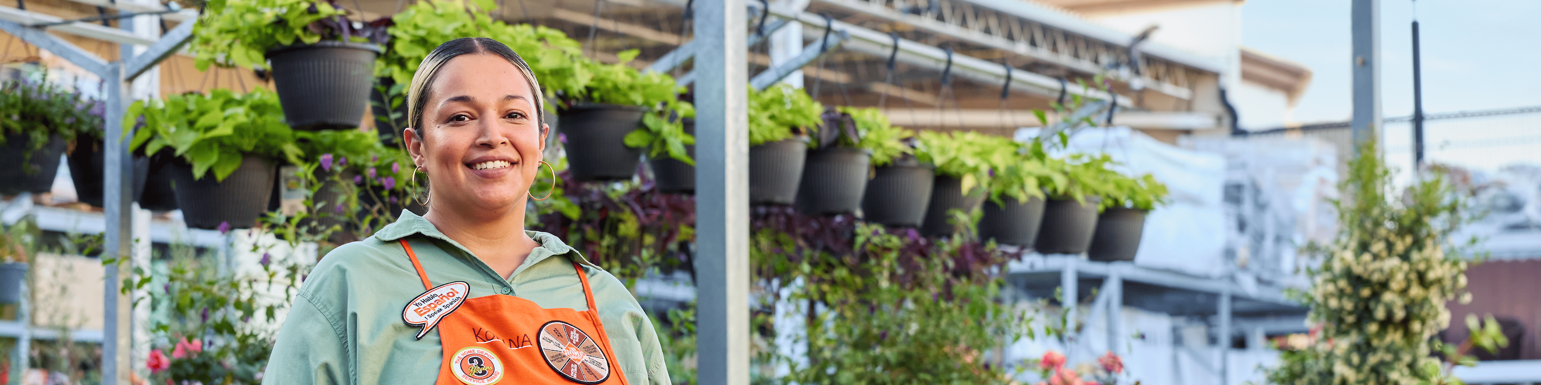 woman wearing The Home Depot apron standing among flowers in a garden center