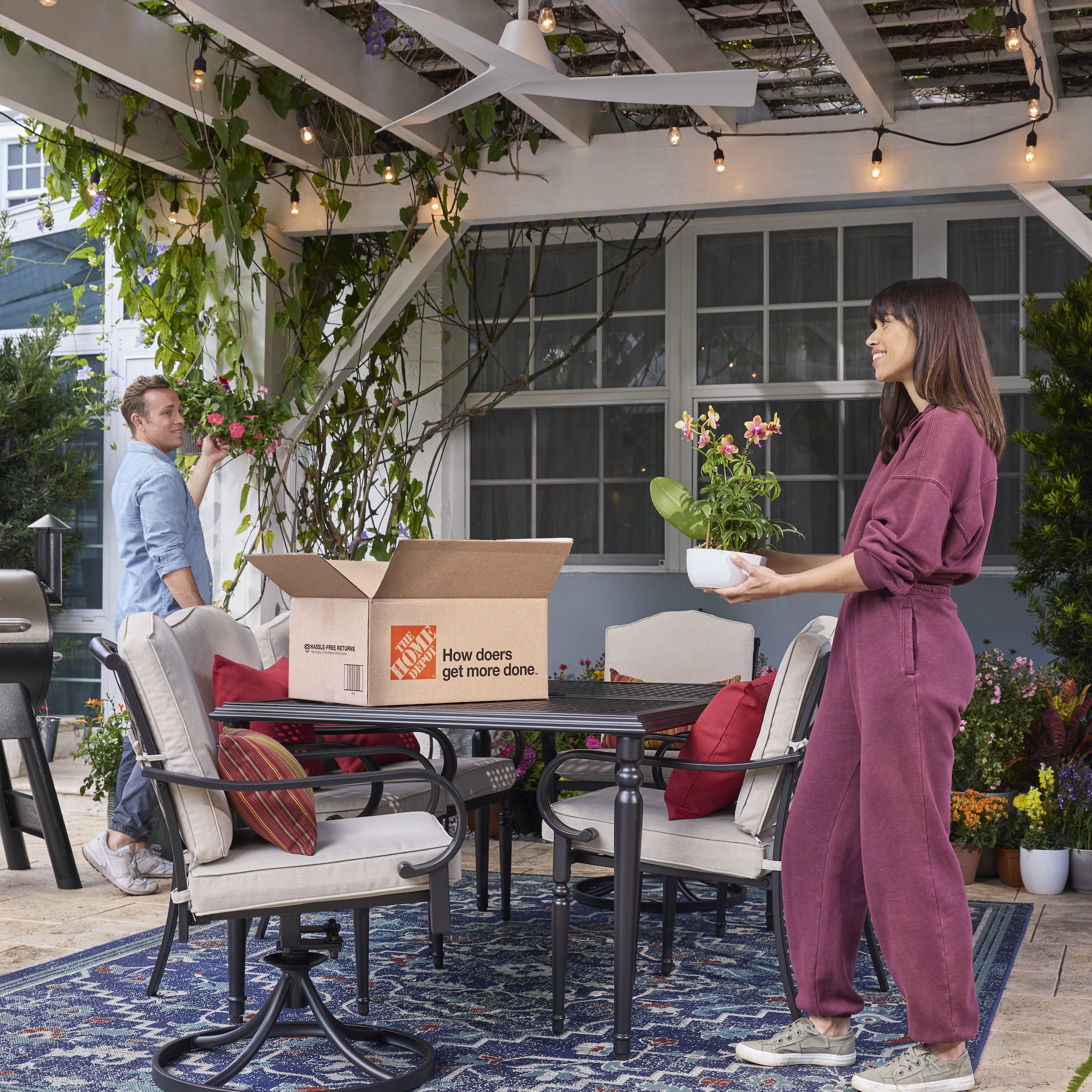 man and woman unpacking a Home Depot box outside on a patio